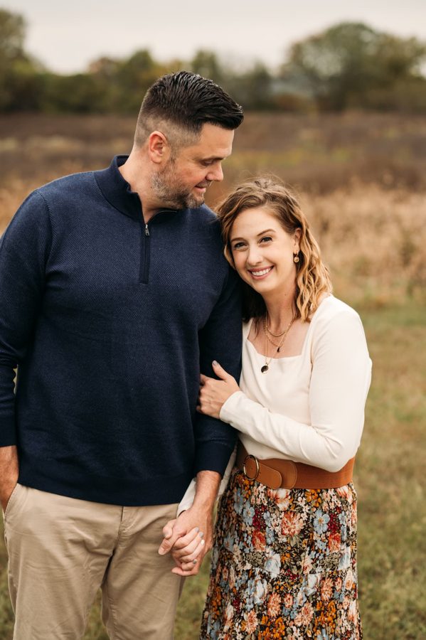 Husband and wife holding hands together in an open Kansas prairie — family photography in the Kansas City area