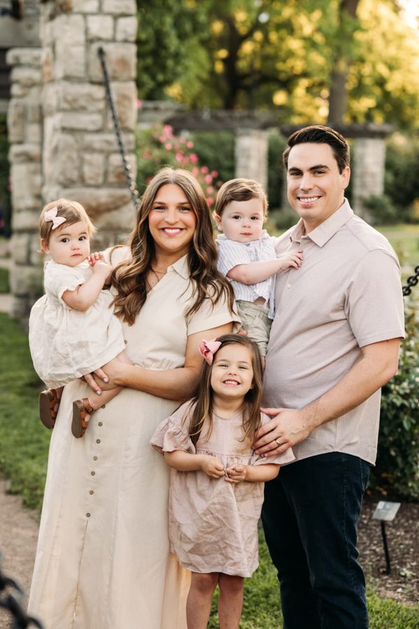 Family of five in soft neutrals beside the rose garden pergola — family photography in the Kansas City area