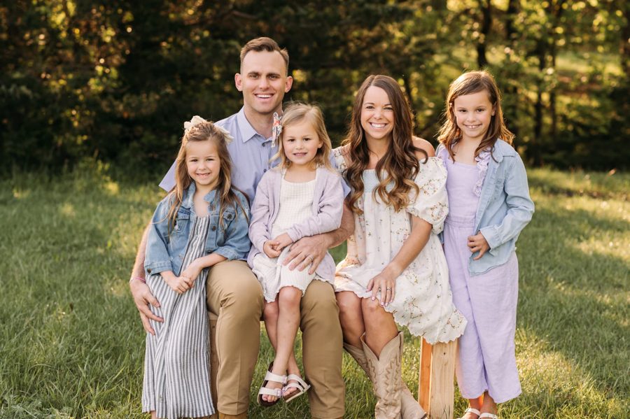 Family of five smiling together in a sunlit Kansas City field — family photography in the Kansas City area