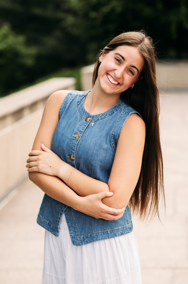 Senior girl in a denim vest laughing on a sunlit walkway — seniors photography in the Kansas City area