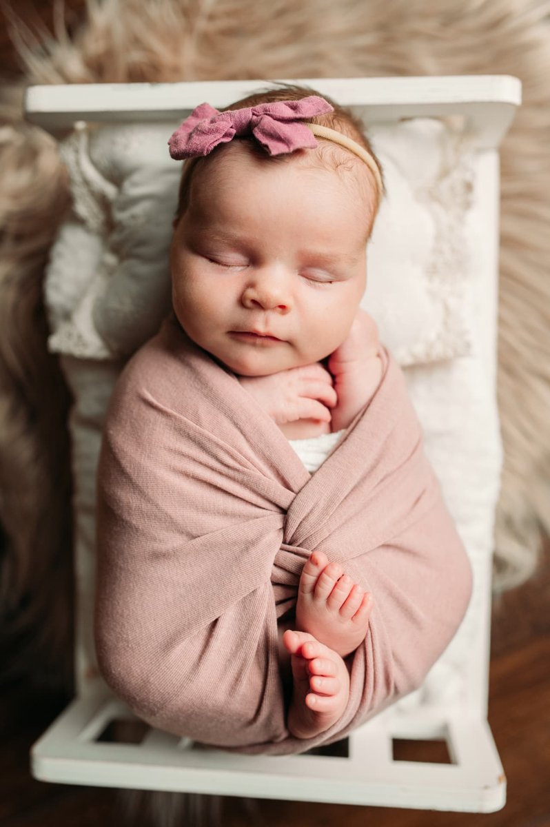 Close-up of a sleeping newborn girl swaddled in mauve with her toes peeking out — newborn photography in the Kansas City area