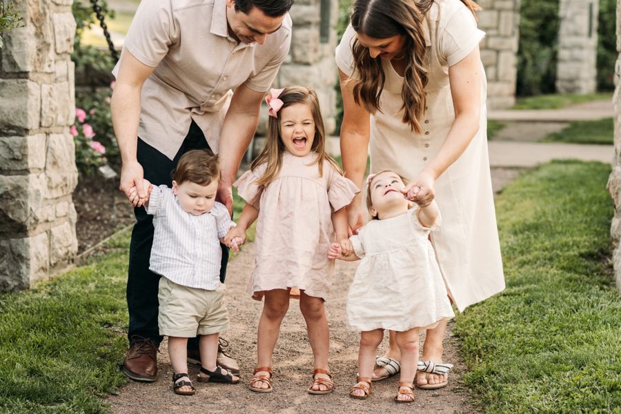Mom and dad steadying their three little ones on a gravel garden path — family photography in the Kansas City area
