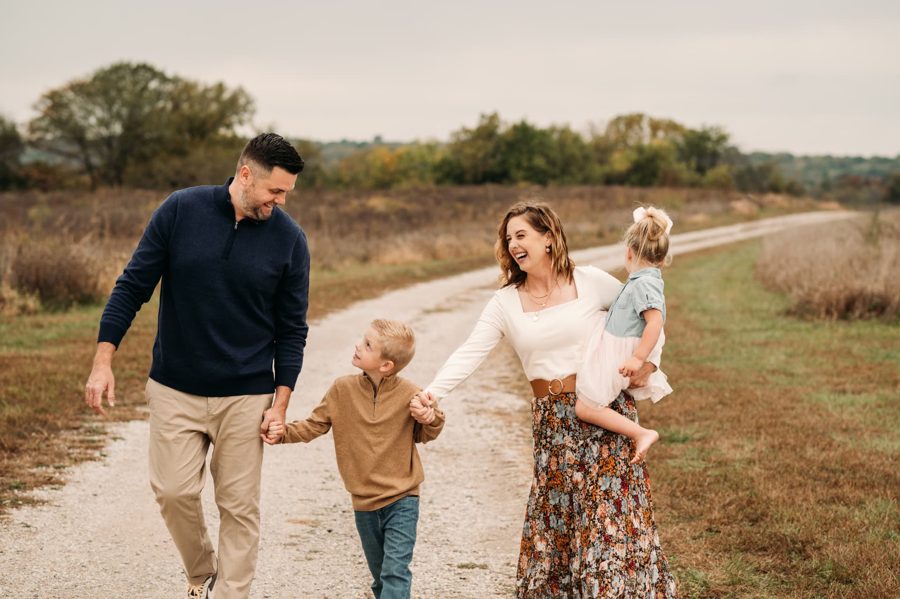 Family of four walking and laughing along a country road — family photography in the Kansas City area
