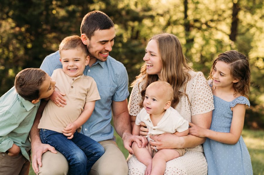 Parents laughing with their four children in golden evening light — family photography in the Kansas City area