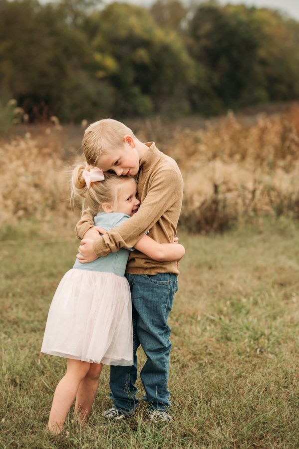 Big brother hugging his little sister in an open field — family photography in the Kansas City area
