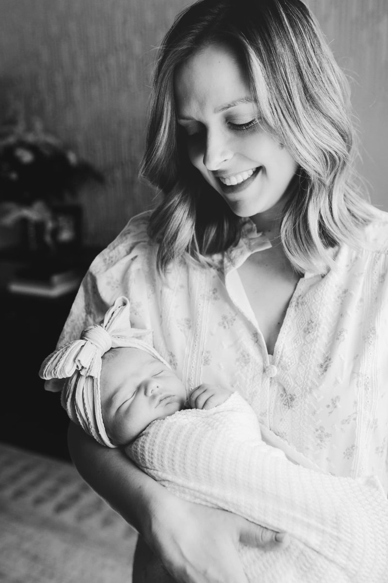 Black and white portrait of a mother smiling at her swaddled newborn daughter — newborn photography in the Kansas City area