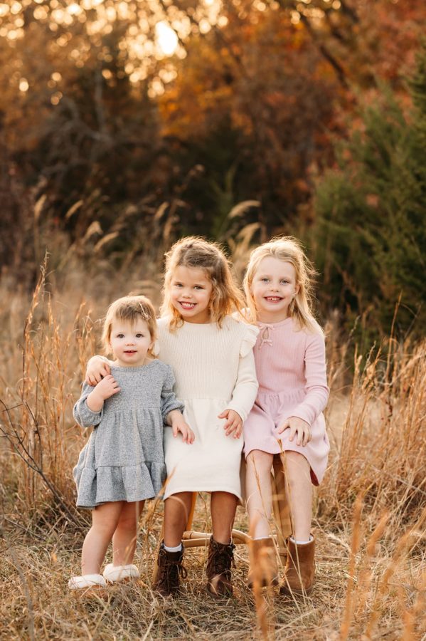 Three little sisters in autumn colors in a golden prairie — family photography in the Kansas City area