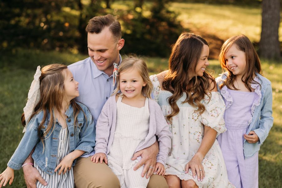 Parents and three daughters laughing together in warm evening sun — family photography in the Kansas City area