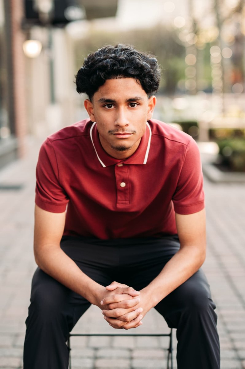 Senior guy in a red polo seated on a downtown sidewalk — seniors photography in the Kansas City area