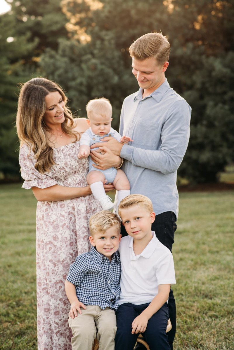 Parents holding their baby while their two boys sit in front at golden hour — family photography in the Kansas City area