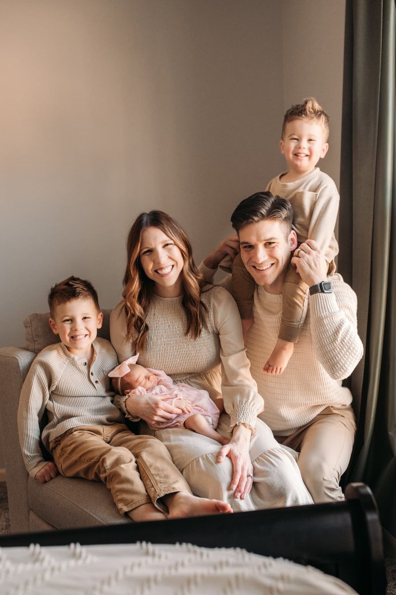 Family of five smiling together with their newborn daughter at home — newborn photography in the Kansas City area