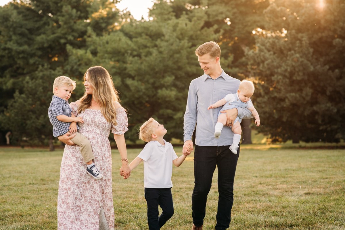 Family of five walking hand in hand through a sunlit park — family photography in the Kansas City area