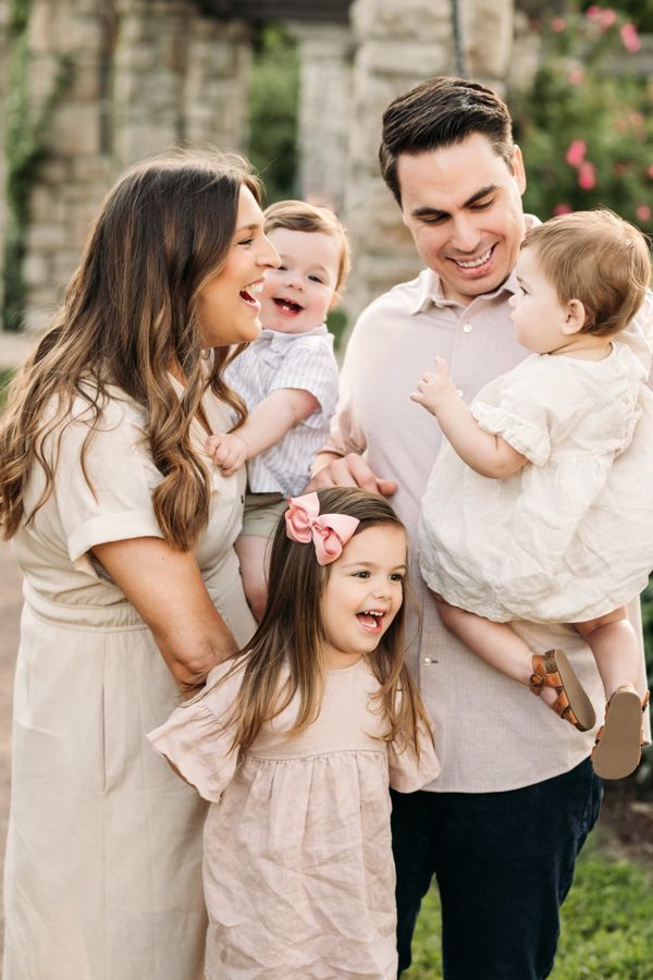 Parents laughing with their three little ones in the Kansas City rose garden — family photography in the Kansas City area