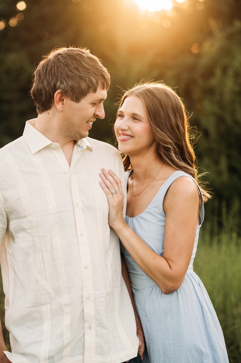 Couple smiling at each other as the sun sets behind them — family photography in the Kansas City area