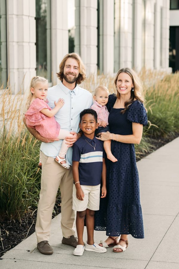 Family of six smiling together beside tall ornamental grasses — family photography in the Kansas City area