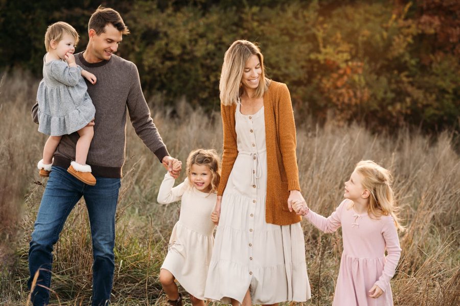 Family of five walking hand in hand through an autumn prairie — family photography in the Kansas City area