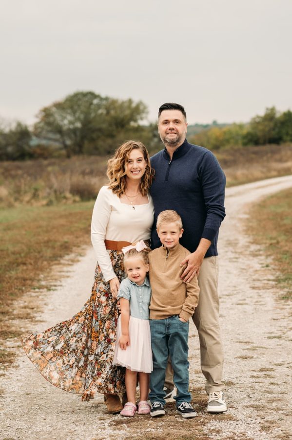 Family of four standing together on a country gravel road — family photography in the Kansas City area
