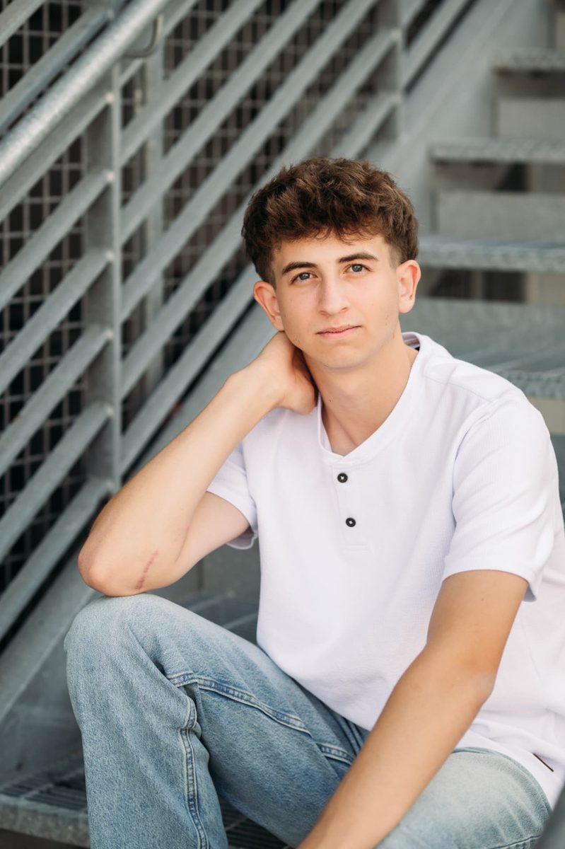 Senior guy in a white henley sitting by a metal staircase