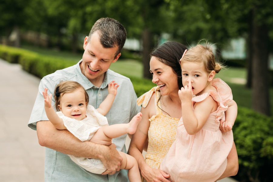 Playful family of four giggling together during a summer park session — family photography in the Kansas City area