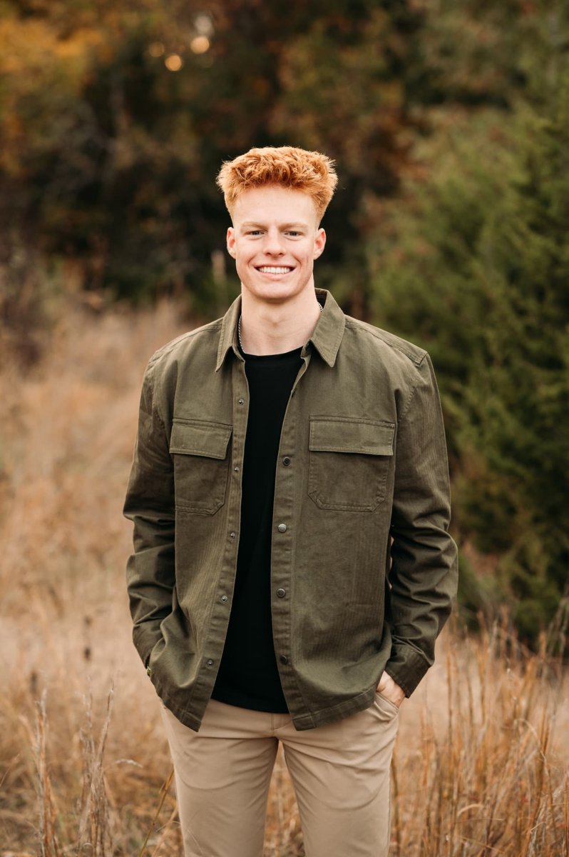 Senior guy in an olive jacket standing in tall autumn grass