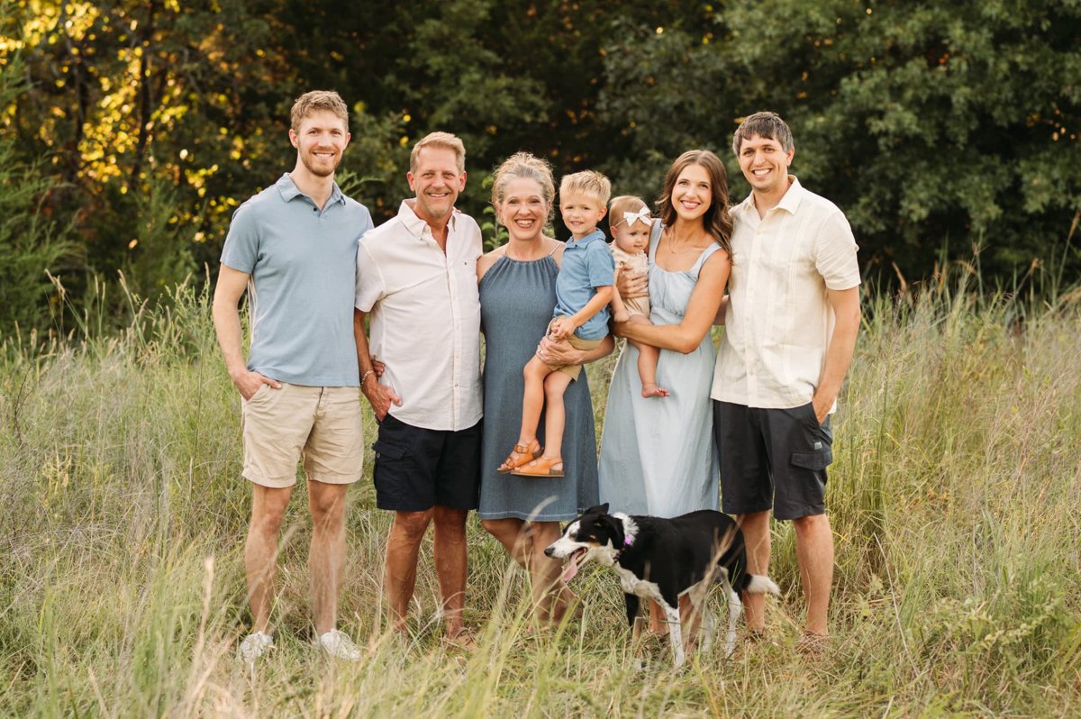 Extended family with grandparents, grandkids, and their dog in a tall summer field — family photography in the Kansas City area
