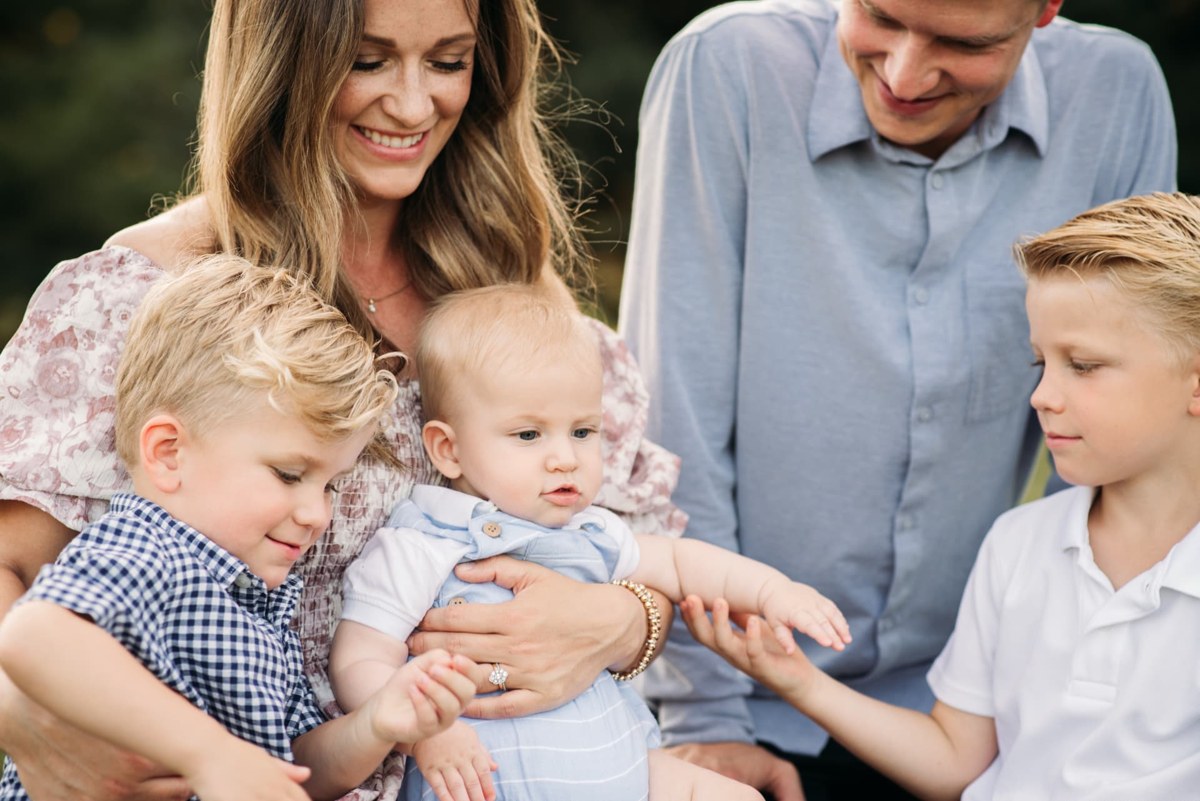 Family gathered around their baby boy, laughing together — family photography in the Kansas City area
