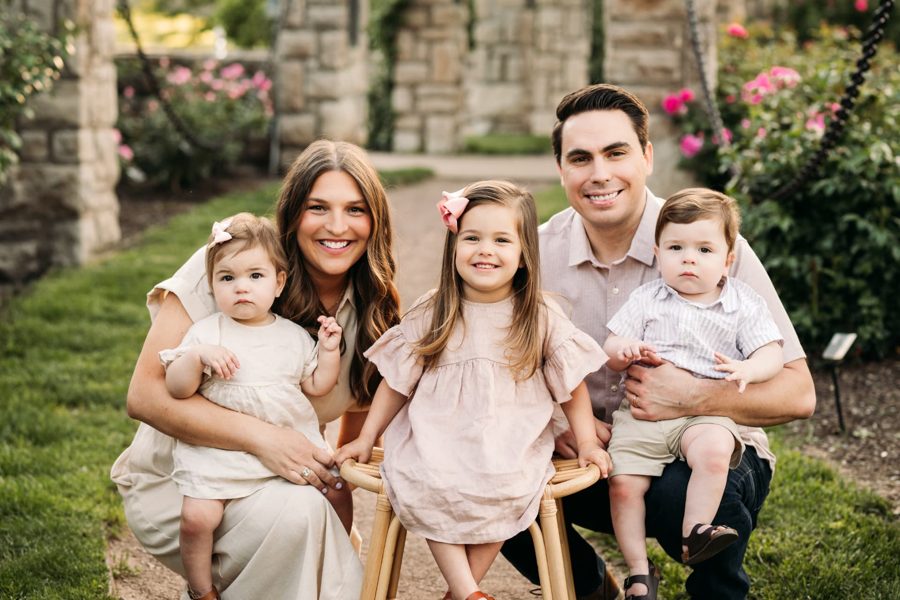 Parents kneeling with their three young children on a garden path — family photography in the Kansas City area