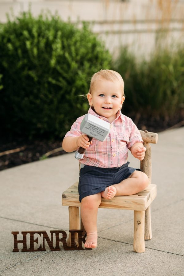 One year old boy sitting on a wooden bench with his name blocks
