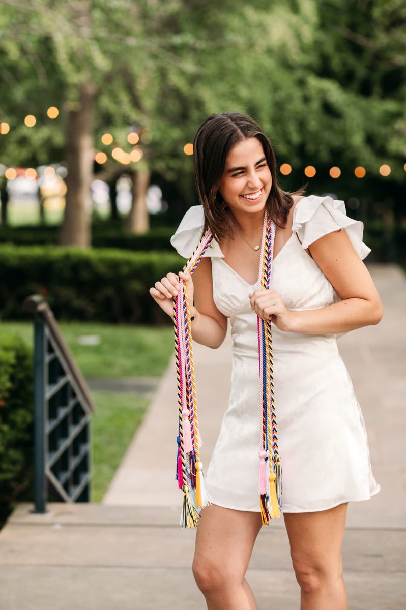 Senior girl holding her graduation cords under string lights — seniors photography in the Kansas City area