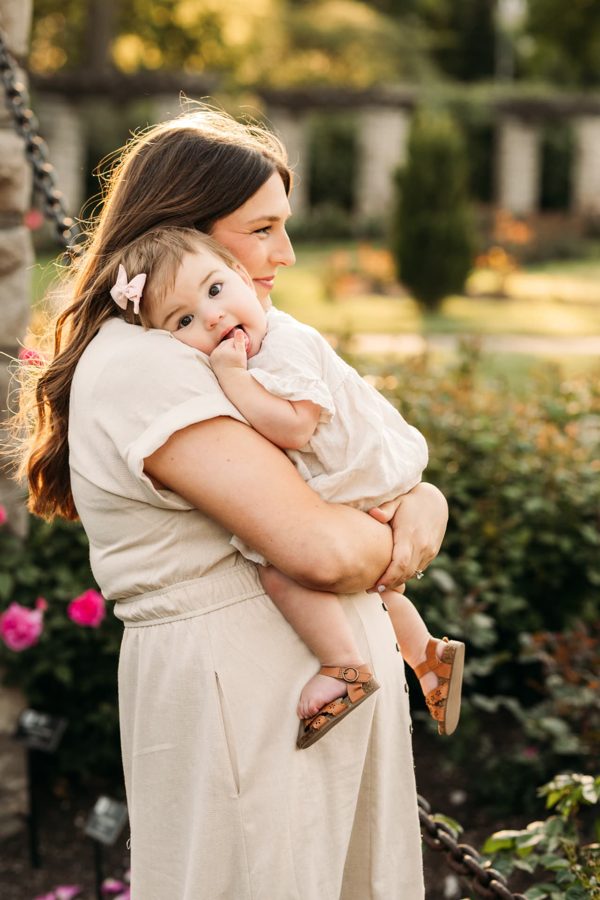 Mom holding her baby girl on the rose garden swing at golden hour — family photography in the Kansas City area