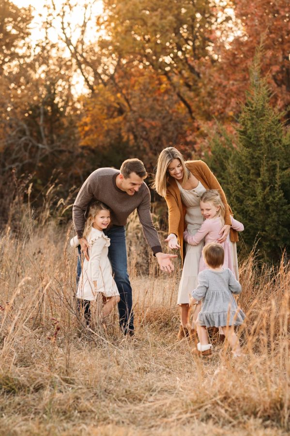 Family playing together in tall autumn grasses at sunset — family photography in the Kansas City area