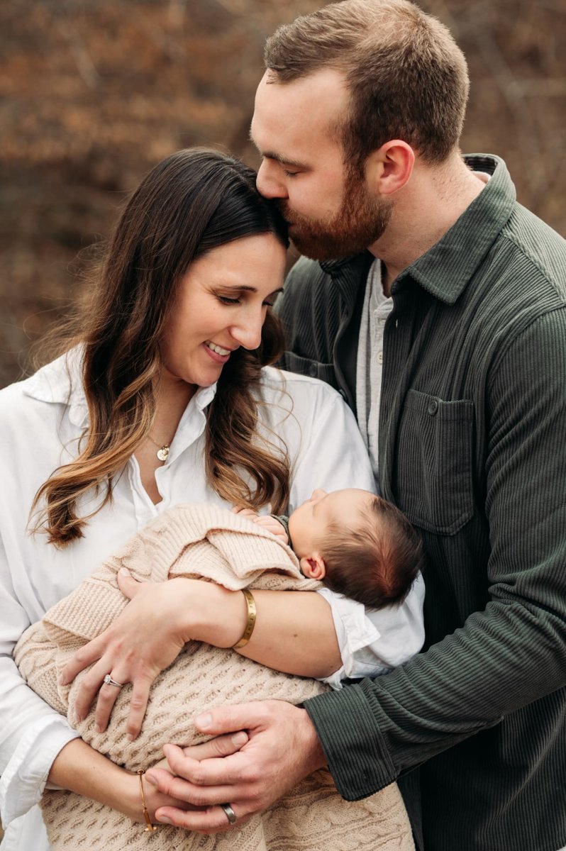 Parents holding their swaddled newborn close on a winter afternoon — newborn photography in the Kansas City area